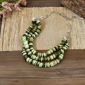 Detailed view of triple-layered green shell bead necklace with silver chain adjustment