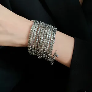 Close-up view of a minimalist silver multi-layer wrap bracelet worn on a wrist.