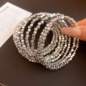 Detail view of a silver square bead multi-layer wrap bracelet held by hand for display