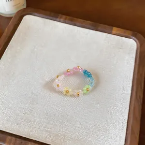 Detailed macro shot of a multi-colored beaded flower ring on a beige linen board
