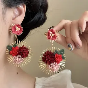 Pendientes de flores de tela con marcos dorados de rayos de sol para un look vacacional.