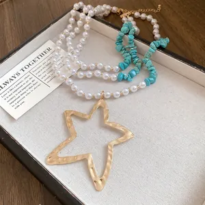 Detail of multi-layer pearl and turquoise necklace with large gold star pendant