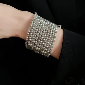 Close-up of a minimalist multi-layer silver bead bracelet on a wrist with black background.