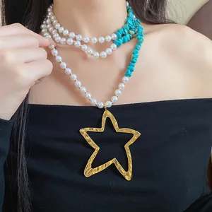 Close-up of a multi-layer pearl and turquoise necklace with a gold star pendant.
