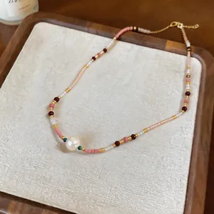 Close-up of a French style beaded necklace with a central pearl on a wooden jewelry tray