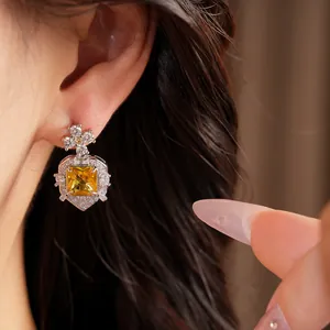 Detail shot of palace style earrings with a square yellow zircon and floral stud