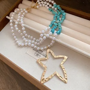 Close-up of vintage multi-layer pearl necklace with a large gold hammered star pendant.