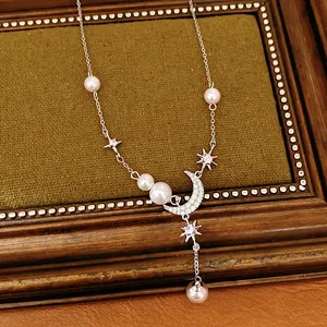 Detail view of an elegant silver necklace with zircon moon pendant, stars and pearls.