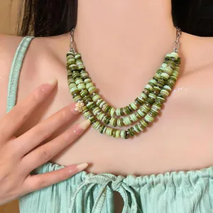 Close-up detail showing textured green shell beads on a multi-layer vintage necklace.