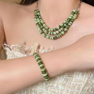 Close-up view of a vintage ethnic style shell bead necklace and bracelet set on a model