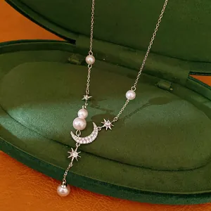 Close-up of elegant star and moon tassel necklace with pearls on green velvet