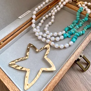 Detailed macro shot of a layered pearl and turquoise necklace with a large gold star pendant.