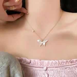 Close-up detail of a delicate gold butterfly necklace with a small pearl accent