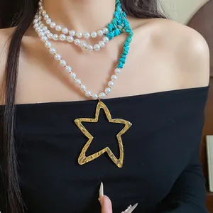 Close-up detail of multi-layer pearl and turquoise necklace with gold star pendant