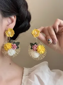 Primer plano detallado de pendientes de flores de tela hechos a mano con detalles dorados