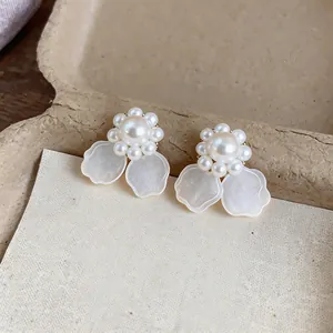 Detalle de elegantes pendientes de perlas en forma de flor con pétalos marmoleados