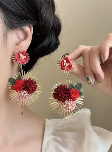 Detalle de pendientes colgantes de flores de tela en rojo vibrante y dorado