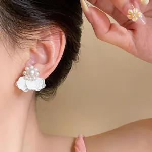 Primer plano detallado de pendiente de flor blanca con perla en modelo