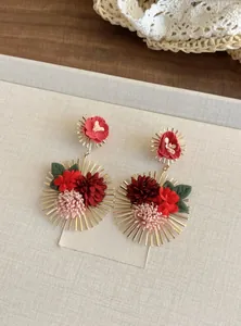 Vista detallada de pendientes florales bohemios con pétalos de tela rojos vibrantes