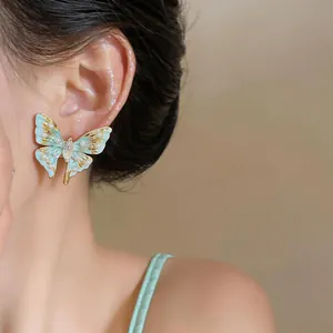 Detailaufnahme eines eleganten minzgrünen Schmetterlingsohrrings mit Perlenbesatz