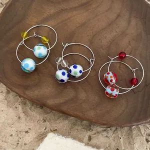 Handmade style colorful polka dot resin bead hoop earrings displayed on wooden plate
