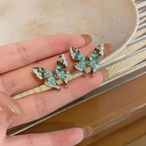 Makro-Detailansicht eleganter grüner Schmetterlings-Ohrstecker mit Perlen und Kristallen