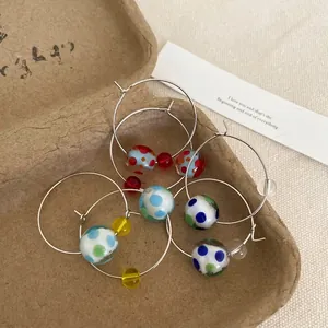 Detailed view of fashionable silver hoop earrings featuring colorful polka dot resin beads