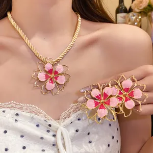 Close-up of a vintage pink enamel flower pendant necklace and earrings set on a model.
