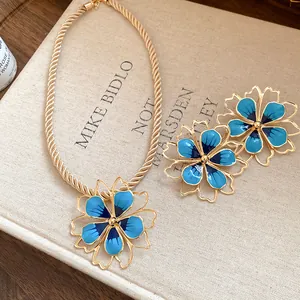 Close-up detail of vintage style blue enamel flower pendant necklace and earring set