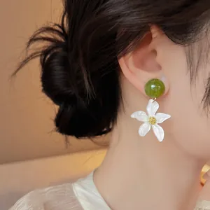 Gros plan de boucles d'oreilles pendantes en forme d'étoile de mer blanche sur l'oreille