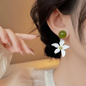 Gros plan détaillé de boucles d'oreilles pendantes étoile de mer blanche et verte.