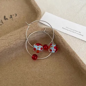 Close-up of dopamine resin hoop earrings featuring blue and red polka dot beads