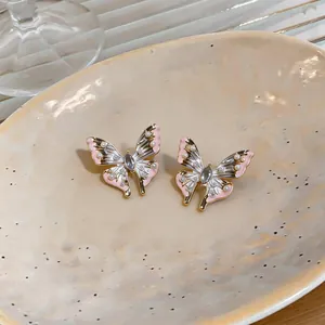 Nahaufnahme von eleganten Schmetterling-Ohrsteckern mit rosa Emaille und Perlendetails