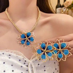 Close-up detail of retro blue enamel flower necklace and earrings set with gold rope chain