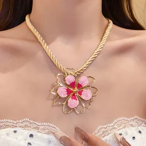 Detailed view of a vintage enamel flower pendant necklace with a gold rope chain