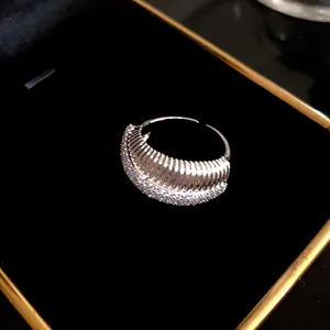 Gros plan d'une bague ouverte plaquée or 14k avec lignes texturées et zircons brillants
