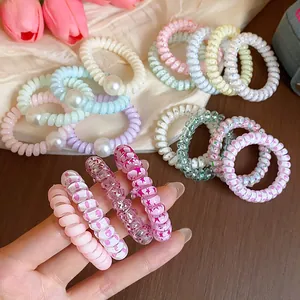 Detailansicht bunter Spiral-Haargummis mit Perlen und Sternenmustern für Damen