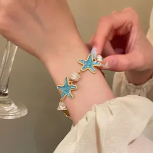 Detailed view of mint green starfish bracelet featuring elegant baroque pearls on wrist