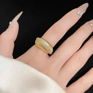 Gros plan détaillé d'une bague ouverte dorée texturée avec des pierres de zircon au doigt