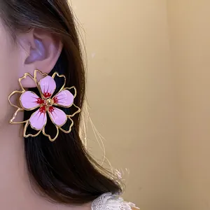 Close-up detail of oversized pink enamel flower earrings worn by an elegant Asian model