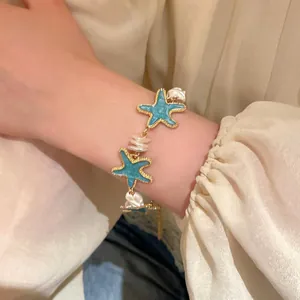 Detailed macro view of an elegant sea star and baroque pearl charm bracelet on a wrist