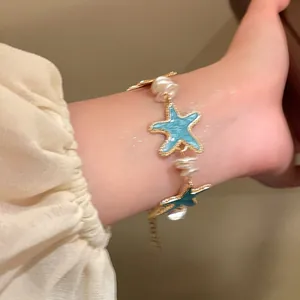 Detailed view of an elegant mint blue starfish bracelet with pearls worn on a wrist.