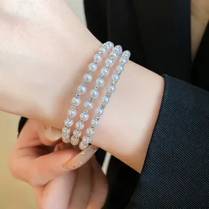 Elegant multi-layer pearl bracelet with sparkling rhinestone spacers on wrist.