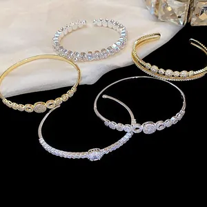 Primer plano de elegantes brazaletes abiertos bañados en oro de 14K con circonitas finas.