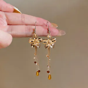 Close-up detail of vintage gold floral hook earrings with elegant long glass bead tassels