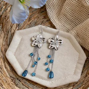 Macro view of French vintage silver flower earrings with elegant blue glass tassel details