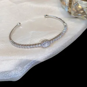 Detalle elegante de un brazalete rígido plateado con brillantes piedras de circonita