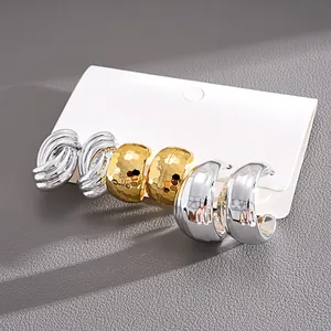 Detail of a 6-piece C-shaped earring set in silver and gold, showing varied textures.