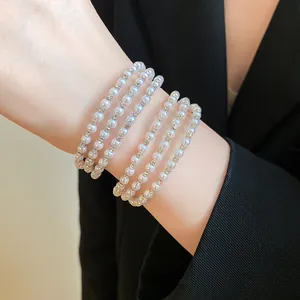 Close-up view of an elegant multi-layer pearl and rhinestone bracelet worn on a wrist.