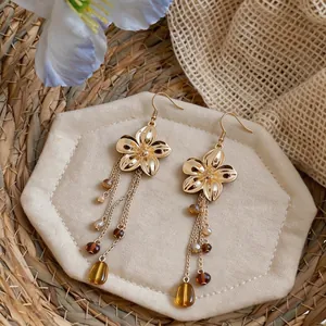 Detailed view of French vintage gold flower earrings with long amber glass bead tassels